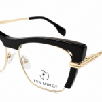 Gold and black designer eyeglasses with metal temples and clear nose pads, Eva Minge branding on the lens area.