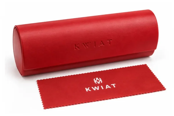 Red cylindrical eyewear case with embossed 'KWIAT' and a matching red cleaning cloth laid next to it.