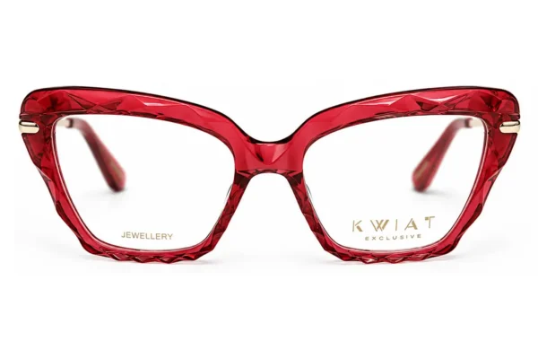 Red faceted-frame eyeglasses seen from the front with gold branding on the lenses (right: 'KWIA T EXCLUSIVE', left: 'JEWELLERY').